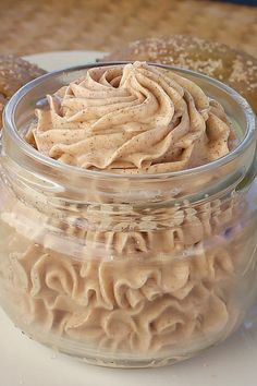 a glass jar filled with food sitting on top of a white plate next to pretzels