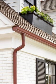 a house with a planter on top of it's gutter hoses