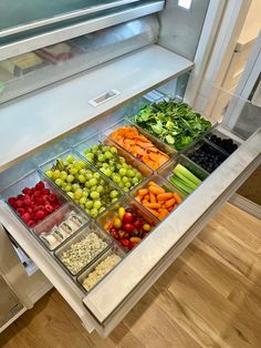 an assortment of fruits and vegetables on display in a refrigerator