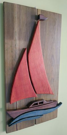 a wooden sailboat mounted to the side of a wood plank wall hanging on a wall