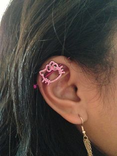 a girl with ear piercings that have pink designs on them