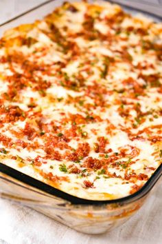 a casserole dish with meat and cheese in it sitting on a white cloth