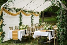 an outdoor tent with tables and chairs set up for a wedding reception in the grass