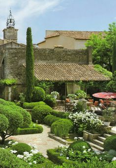 an outdoor patio with potted plants and tables in the foreground, surrounded by trees