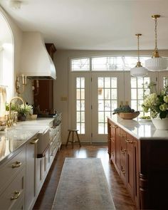 a large kitchen with wooden floors and white walls, along with an arched glass door that leads to the outside patio