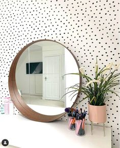 a mirror sitting on top of a dresser next to a potted plant and vase