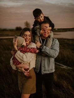 a man, woman and child are posing for a photo in a field at sunset