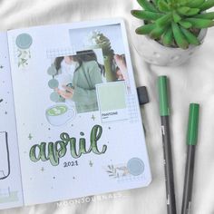 an open planner book sitting on top of a bed next to a potted plant