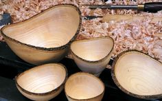 several bowls are lined up next to each other on a table covered in wood shavings