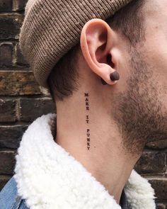 a man with a tattoo on his neck and behind the ear is a brick wall