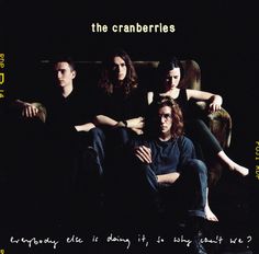 the cranberries sitting on a couch with their arms crossed in front of them