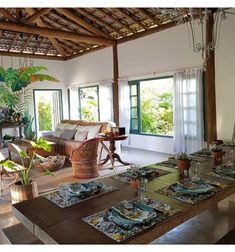 a living room filled with lots of furniture and plants on top of wooden flooring