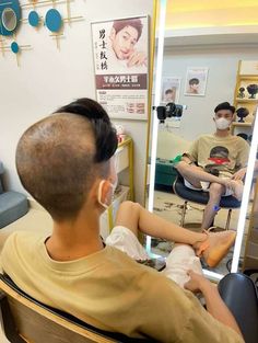 a man sitting in front of a mirror while getting his hair cut