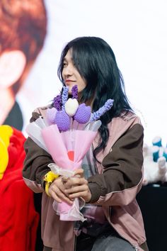 a woman sitting down with flowers in her hand