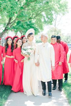 a group of people standing next to each other in front of some trees and grass