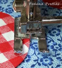 the sewing machine is on top of the fabric with red and white checkered tablecloth