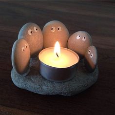 an image of a candle that is in the middle of rocks with faces on it