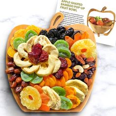 a wooden heart shaped platter filled with dried fruit and veggies for a healthy snack