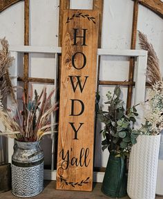 a wooden sign sitting on top of a shelf next to potted plants and vases