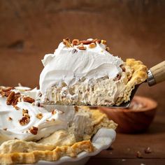 a piece of pie with whipped cream and pecans on top is being held by a fork