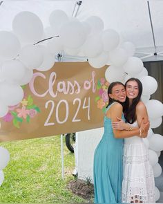 two girls hugging each other in front of a sign that says class of 2021 on it