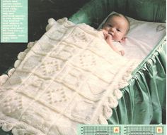 a baby laying in a crocheted blanket on top of a green bed sheet