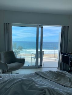 a bed room with a neatly made bed and an open sliding glass door leading to the beach