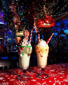 two ice cream sundaes sitting on top of a table covered in christmas lights