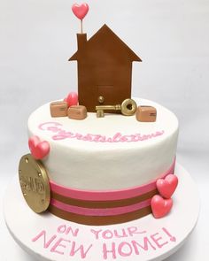 a white cake with pink and brown decorations on top that says congratulations on your new home