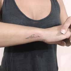 a woman's arm with a small wave tattoo on the left side of her arm