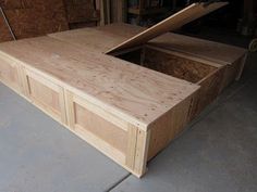 a wooden box sitting on top of a cement floor next to plywood planks