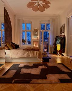 a bed room with a neatly made bed next to two windows and a rug on the floor