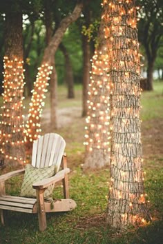 a white chair sitting next to a tree covered in lights