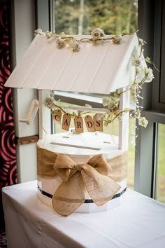 a white cake with a bow on top sitting on a table in front of a window