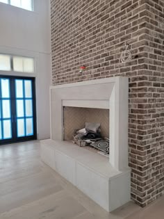 an empty fireplace in the middle of a large room with brick walls and floor to ceiling windows