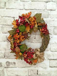 a wreath on a brick wall decorated with autumn leaves and foliage, hanging from the side