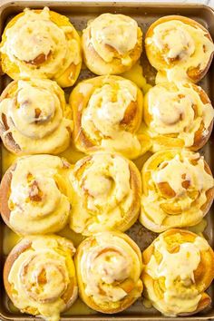 a baking pan filled with cinnamon rolls covered in yellow icing and sitting on a table