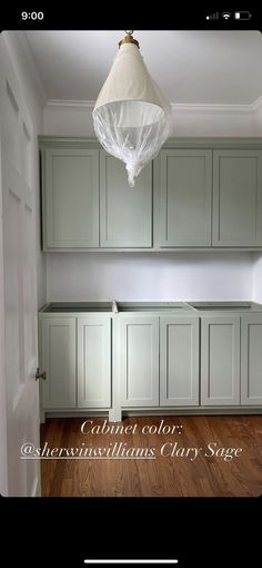 an empty kitchen with white cabinets and wood floors in the center is a light fixture that hangs from the ceiling