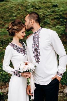 a man and woman standing next to each other with flowers in their hands, both wearing white