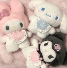 three stuffed animals laying on top of a pink blanket with white and black ones next to each other