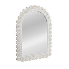 a white wall mirror with scalloped edges