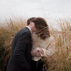 a man and woman are kissing in the tall red grass, with their heads touching each other