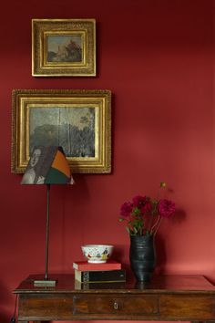 a room with red walls and pictures on the wall, including a table with flowers