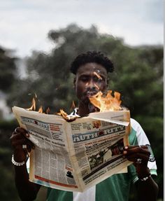 a man holding a newspaper in front of his face with flames coming out of it