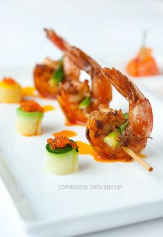 shrimp and vegetable skewers on a white plate with garnishes in the foreground