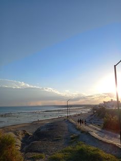 people walking along the beach at sunset