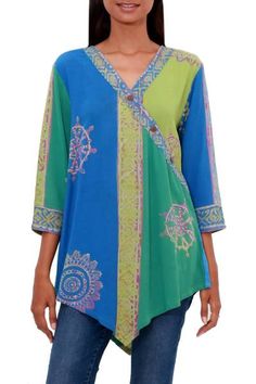 This beautiful textured rayon tunic combines ease and comfort with gorgeous color. Designed by Wayan Arta and Sharon of Bali the tunic features hand-stamped batik motifs in wisteria on blocks of lime green and Caribbean blue. The relaxed fit tunic has a banded V-neck accented with coconut shell buttons three-quarter length sleeves with banded cuffs and a hem that flows to a point at the front and back. Green Batik Print Kaftan, Multicolor Tunic Sets With Printed Motifs, Green V-neck Batik Print Dress, Multicolor V-neck Kaftan With Batik Print, Multicolor Batik Print Kaftan For Beach Cover-up, Batik Clothing, Fitted Tunic, Batik Art, Caribbean Blue