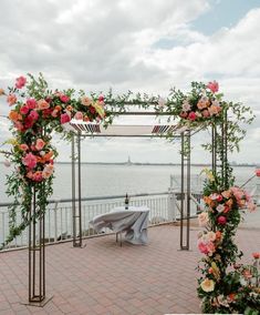 an outdoor wedding ceremony setup with flowers and greenery on the side of the water