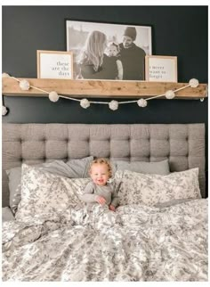 a small child laying on top of a bed in a room with pictures above it