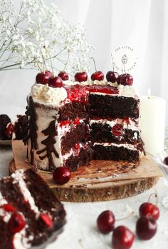 a cake with cherries and whipped cream is on a cutting board next to a candle